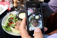 Un hombre fotografiando su plato de comida con su teléfono móvil, el 19 de julio de 2012 en París. Un hombre fotografiando su plato de comida con su teléfono móvil, el 19 de julio de 2012 en París.